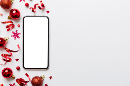 Christmas online shopping from home phone with blank white display top view. smart mobile with copy space on colored background with Christmas decorations balls,. Winter holidays sales background.の写真素材