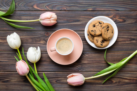 Cup of coffee mug with coffee, cookies and tulips on a colored background. Greeting spring card top view.の写真素材