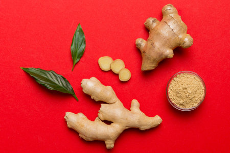 Finely dry Ginger powder in bowl with green leaves isolated on colored background. top view flat...