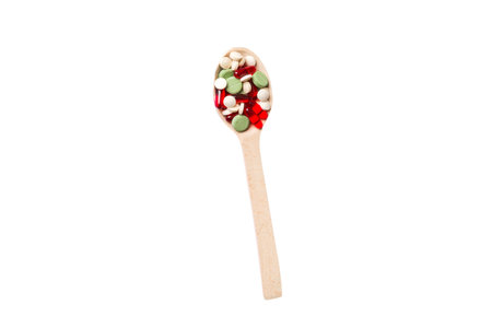 Vitamin capsules in a wooden spoon on a colored background. Pills served as a healthy meal. Drugs,...