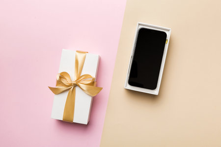 Opened gift box with gold ribbon and smartphone on color background, top view. Blank open box packaging mockup , Template for your design - branding mockup.の写真素材