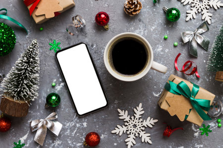 top view of smart phone with hot cup of coffee. Christmas decoration on colored background.