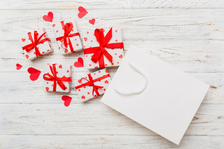 Gift boxes pop out from paper bag top view on colored background. bag packing handmade boxes fall out Concept of holidays, shopping, sale, discounts. Top view, flat lay.の写真素材