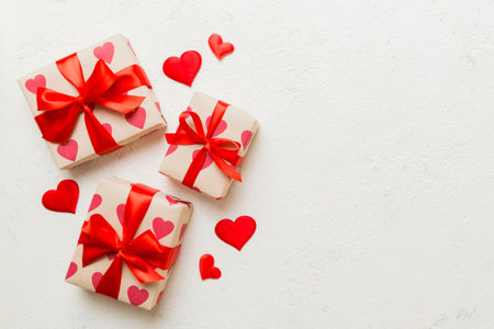 Top view photo of valentine day decorations gift box with red ribbon bow on colored background. Holiday gift boxes with top view.の写真素材