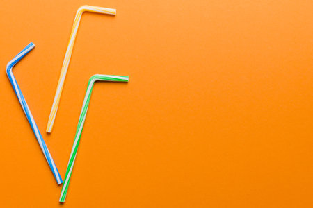 Drinking straws for party on Colored background. Top view of colorful plastic disposable straws for summer cocktails. different straws for juice with copy space.の写真素材