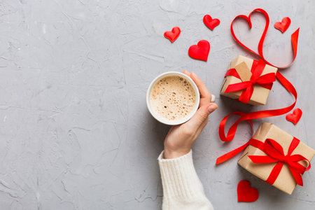 Flat lay of heart shaped cup of black coffee in the hands of women on colored background with copy space top view. Valentine day and holiday concept.の写真素材