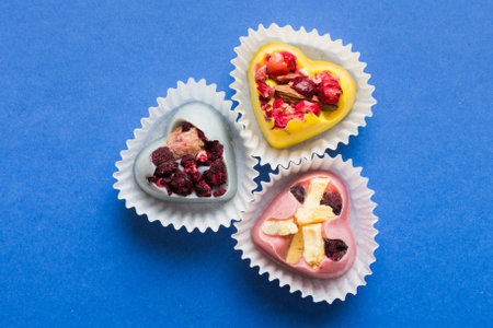 chocolate sweets in the form of a heart with fruits and nuts on a colored background. top view with space for text, holiday concept.の写真素材