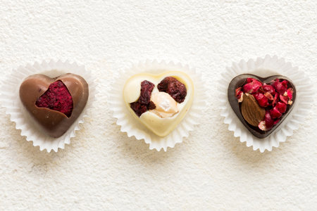 chocolate sweets in the form of a heart with fruits and nuts on a colored background. top view with space for text, holiday concept.の写真素材