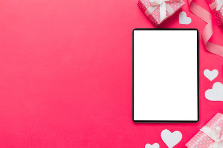 Top view of digital tablet with gift boxes and hearts on colorful background. Tablet with black screen with Holiday decorations gift box top view.の写真素材