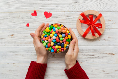 Female hands with delicious candies in box on color background.の写真素材