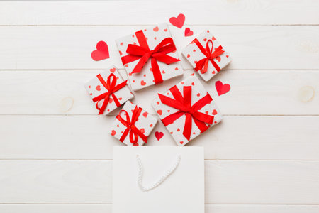 Gift boxes pop out from paper bag top view on colored background. bag packing handmade boxes fall out Concept of holidays, shopping, sale, discounts. Top view, flat lay.の写真素材