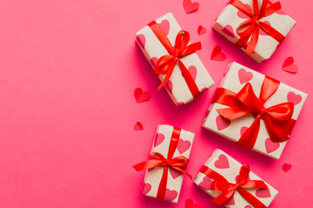 Top view photo of valentine day decorations gift box with red ribbon bow on colored background....