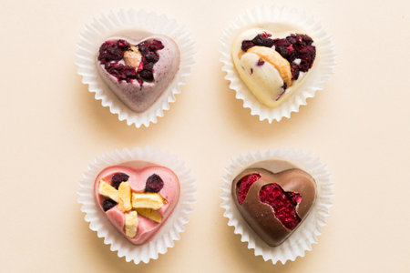 chocolate sweets in the form of a heart with fruits and nuts on a colored background. top view with space for text, holiday concept.の写真素材