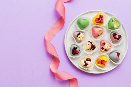 Holiday composition: sweet candy, with gift boxes with bow and chocolate hearts, photo template,...