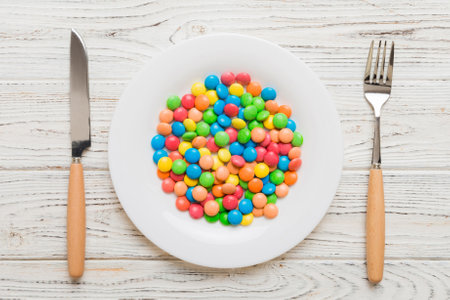 cutlery on table and sweet plate of candy. Health and obesity concept, top view on colored background.の写真素材