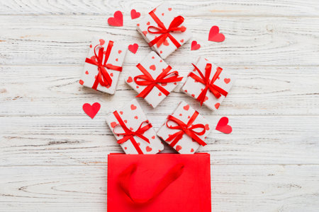 Gift boxes pop out from paper bag top view on colored background. bag packing handmade boxes fall out Concept of holidays, shopping, sale, discounts. Top view, flat lay.の写真素材