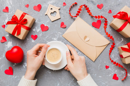 Flat lay of heart shaped cup of black coffee in the hands of women on colored background with copy space top view. Valentine day and holiday concept.の写真素材
