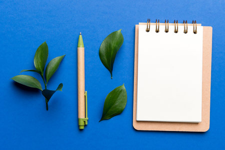 eco-friendly Empty notebook with pen and green leaf on Colored background for note.の写真素材