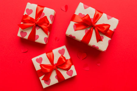 Top view photo of valentine day decorations gift box with red ribbon bow on colored background....
