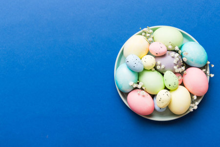 Happy Easter composition. Easter eggs in basket on colored table with gypsophila. Natural dyed colorful eggs background top view with copy space.の写真素材