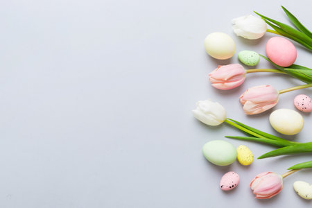 Happy Easter composition. Easter eggs on colored table with yellow Tulips. Natural dyed colorful eggs background top view with copy space.の写真素材