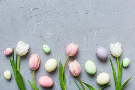 Happy Easter composition. Easter eggs on colored table with yellow Tulips. Natural dyed colorful...