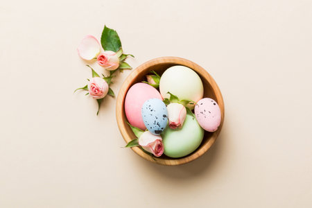Happy Easter. Easter eggs in basket on colored table with yellow roses. Natural dyed colorful eggs...