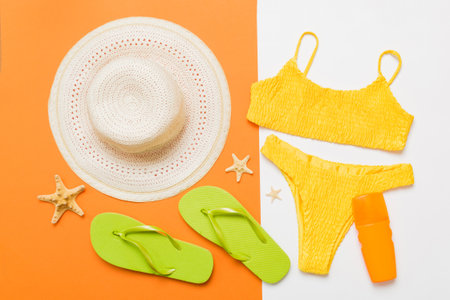 Woman swimwear and beach accessories flat lay top view. Top view with bikini outfit on color...