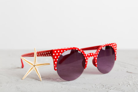 sunglasses with seashell lying on table background. Sunglasses on summer background. Top view flat...