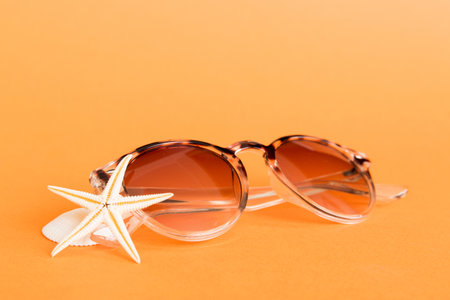 sunglasses with seashell lying on table background. Sunglasses on summer background. Top view flat lay with copy space for text.の写真素材