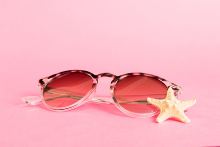 sunglasses with seashell lying on table background. Sunglasses on summer background. Top view flat lay with copy space for text.の写真素材