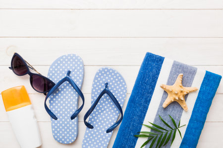 Summer holiday concept. Top view of beach towel, flip flop and sunscreen cream Top view with copy...