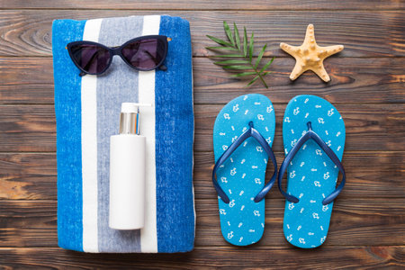 Summer holiday concept. Top view of beach towel, flip flop and sunscreen cream Top view with copy...