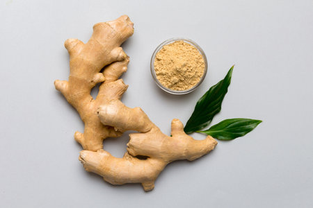 Finely dry Ginger powder in bowl with green leaves isolated on colored background. top view flat lay.の写真素材