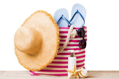 Stylish bag with beach accessories. Summer holiday concept. Top view of beach bag with sunscreen cream with space for text.の写真素材