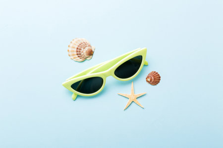 sunglasses with seashell lying on table background. Sunglasses on summer background. Top view flat...