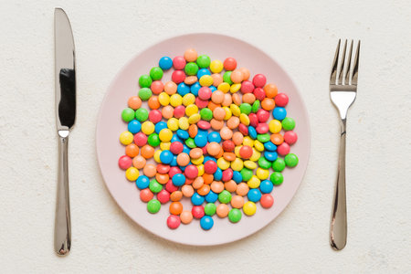 cutlery on table and sweet plate of candy. Health and obesity concept, top view on colored background.の写真素材