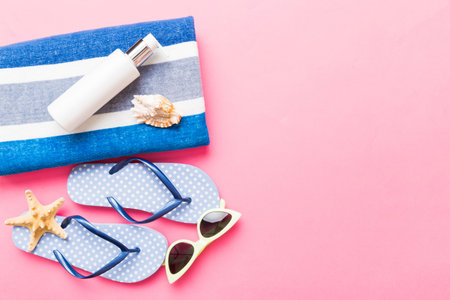 Summer holiday concept. Top view of beach towel, flip flop and sunscreen cream Top view with copy...