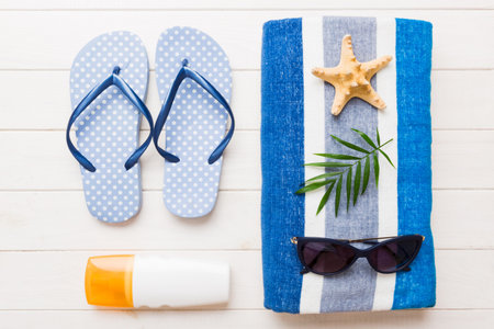 Summer holiday concept. Top view of beach towel, flip flop and sunscreen cream Top view with copy space for text.の写真素材