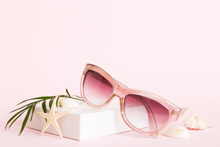 sunglasses with seashell lying on table background. Sunglasses on summer background. Top view flat...