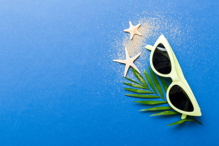 sunglasses with seashell lying on table background. Sunglasses on summer background. Top view flat...