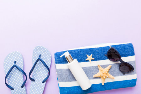 Summer holiday concept. Top view of beach towel, flip flop and sunscreen cream Top view with copy...