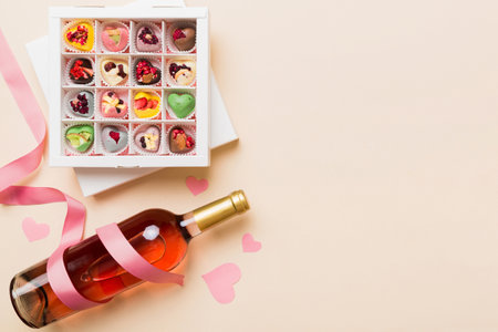 Bottle of red wine on colored background for Valentine Day with gift and chocolate. Heart shaped with gift box of chocolates top view with copy space.の写真素材