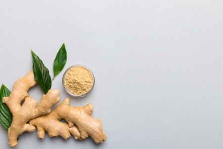 Finely dry Ginger powder in bowl with green leaves isolated on colored background. top view flat...