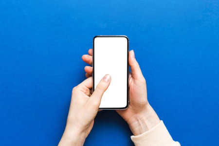 Top view of woman hands holding smart phone with blank copy space screen for your text message or information content. woman hand using phone white screen on top view.の写真素材