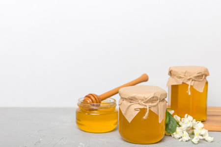 Honey jars with acacia blossoms on colored table.の写真素材