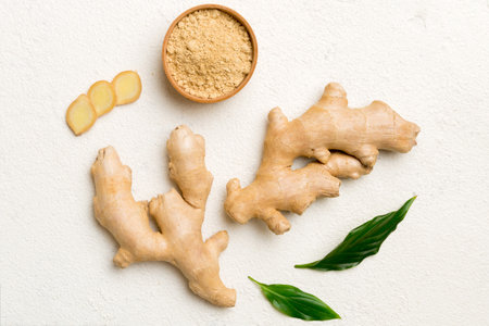 Finely dry Ginger powder in bowl with green leaves isolated on colored background. top view flat...