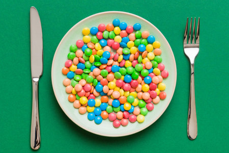 cutlery on table and sweet plate of candy. Health and obesity concept, top view on colored background.の写真素材