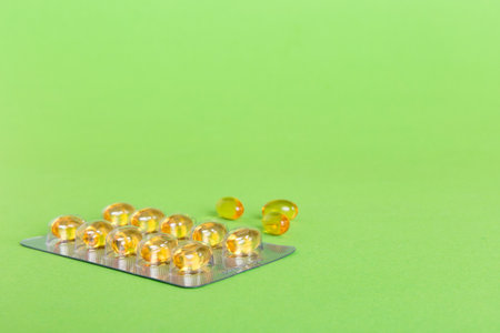 Blister package with fish oil capsules on color background. Medicine pills on a light background. Medicines and prescription pills flat lay background. Yellow medical tablets in blister.の写真素材