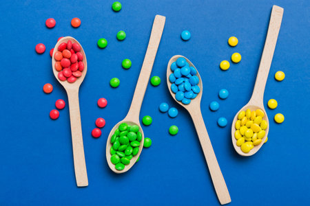 delicious colorful sweet candies on spoon on colored background. Confectionery decor top view with copy space.の写真素材